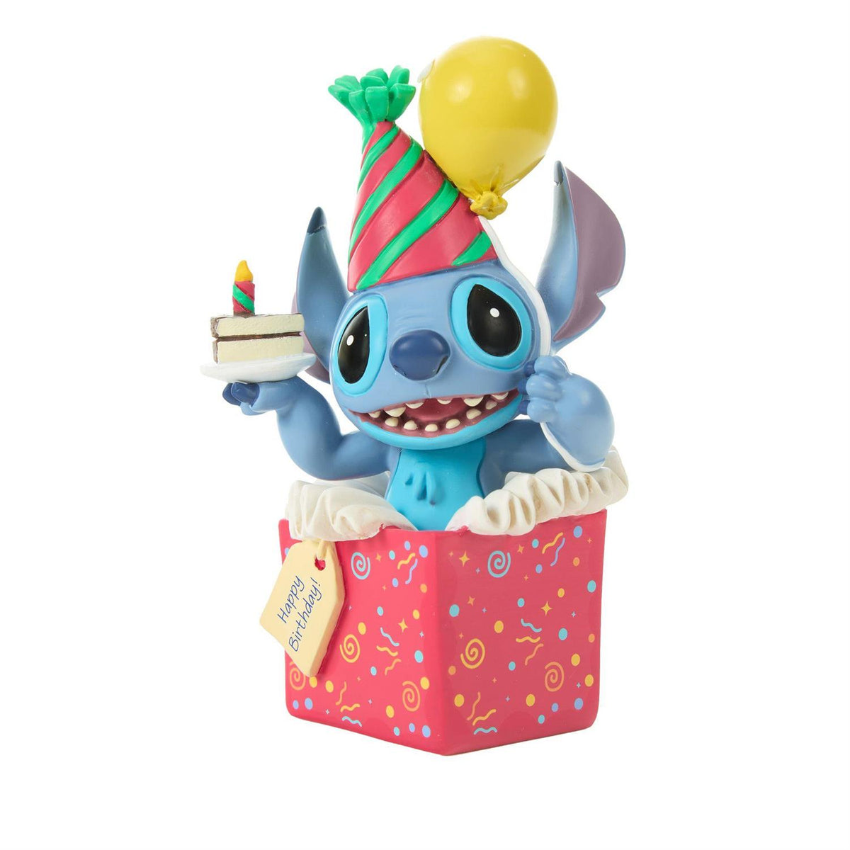 Stitch popping out of a present wearing a birthday hat and holding a piece of cake