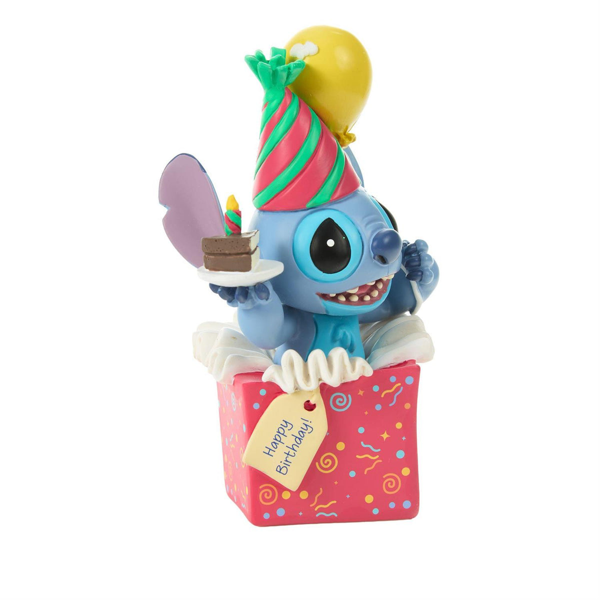 Stitch popping out of a present wearing a birthday hat and holding a piece of cake