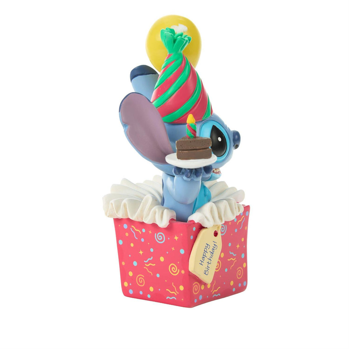 Stitch popping out of a present wearing a birthday hat and holding a piece of cake