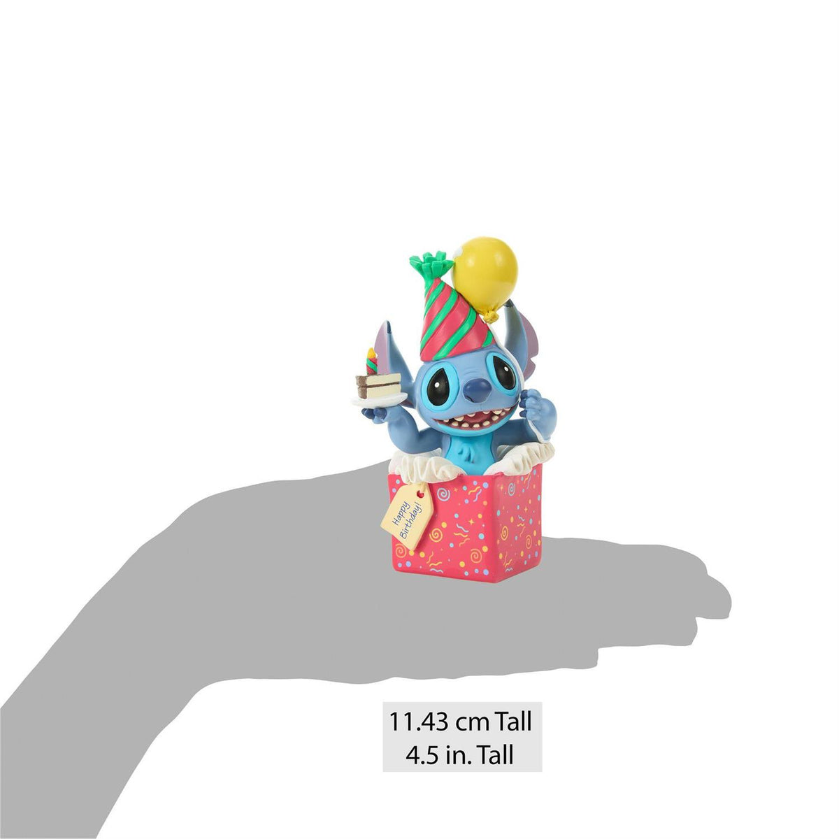 Stitch popping out of a present wearing a birthday hat and holding a piece of cake