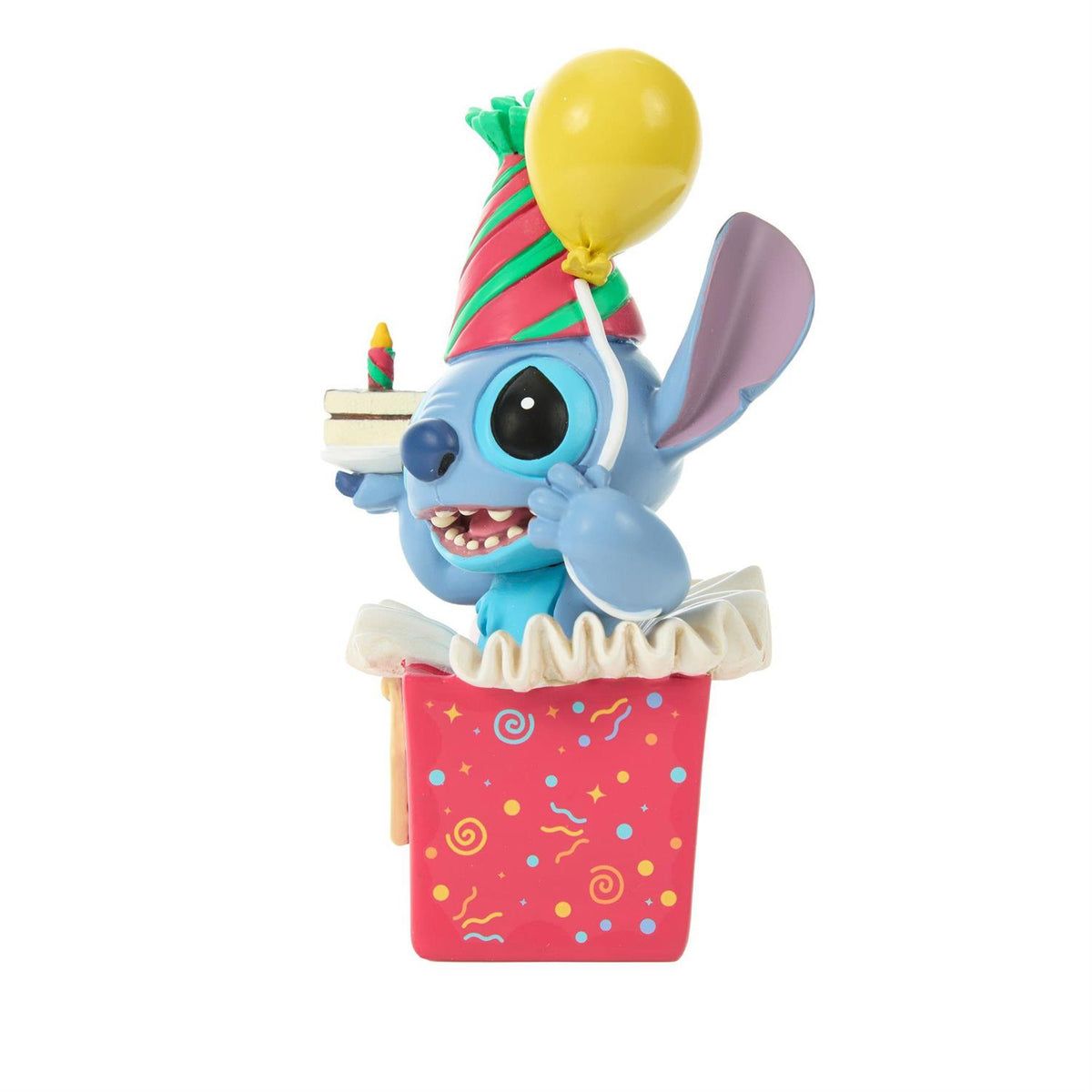 Stitch popping out of a present wearing a birthday hat and holding a piece of cake