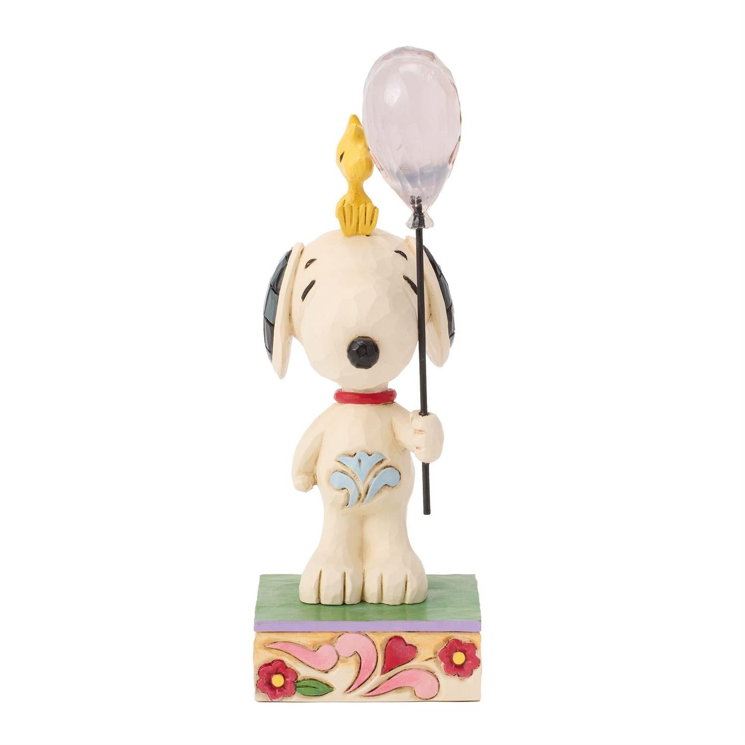 Snoopy holding a heart balloon while Woodstock sitting on his head