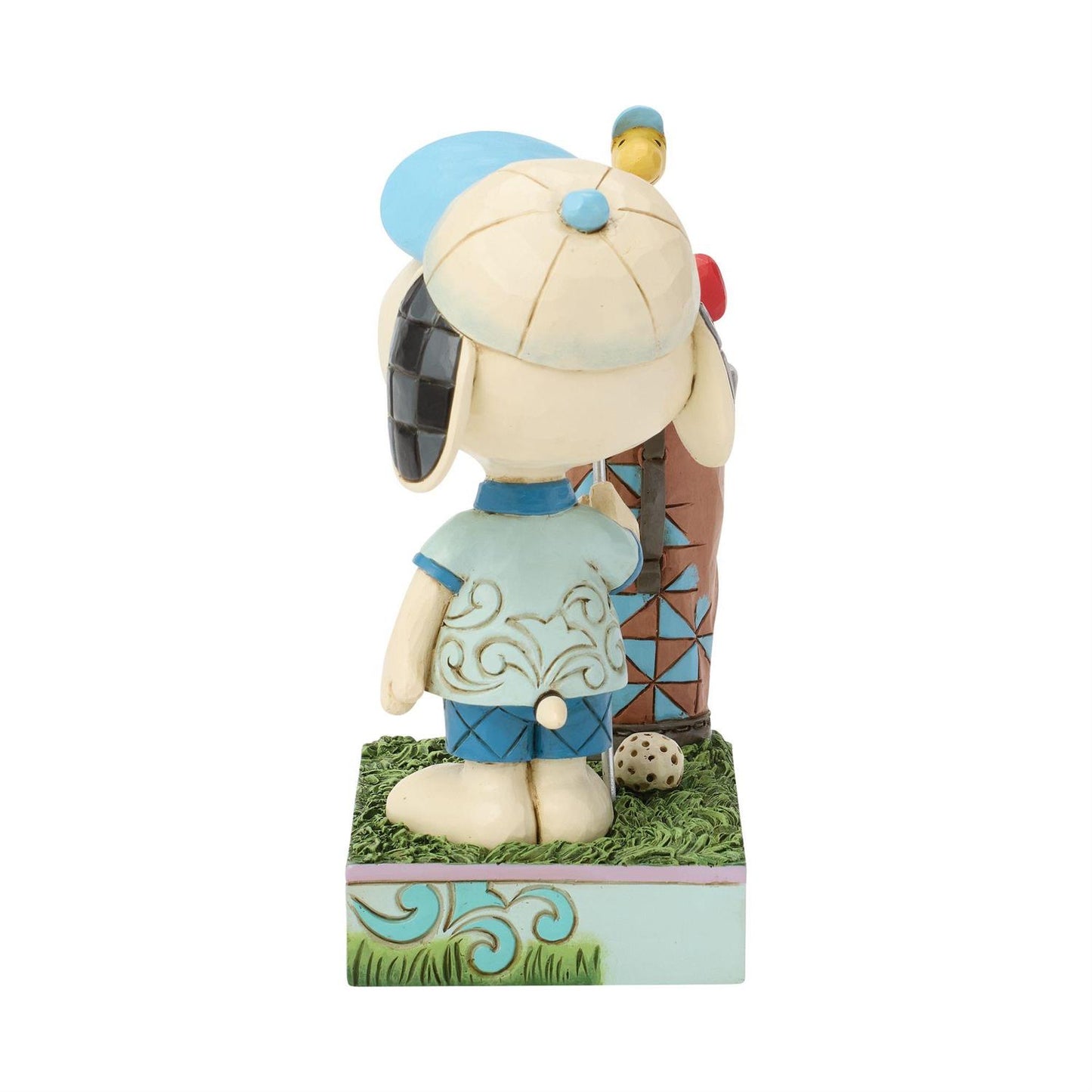 Snoopy dressed in his Golf clothes holding a Golf Club standing next to a Golf bag while Woodstock sits on the Golf Clubs and watches