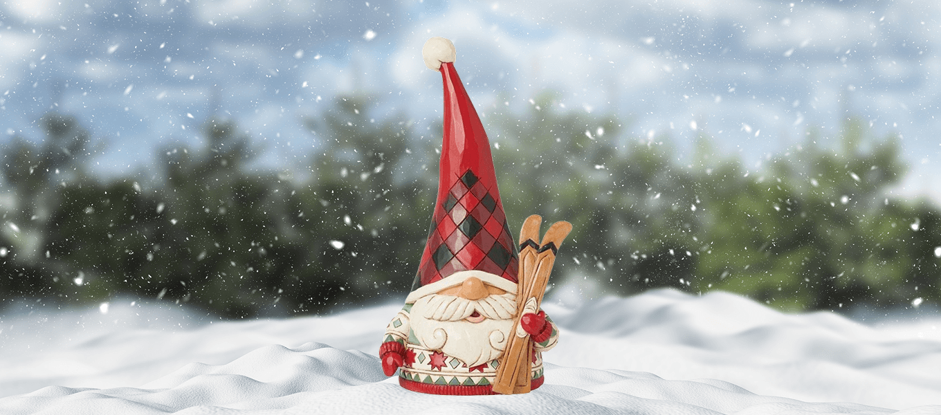 Decorative gnome figure with a red hat and checkered pattern standing in the snow with trees in the background.